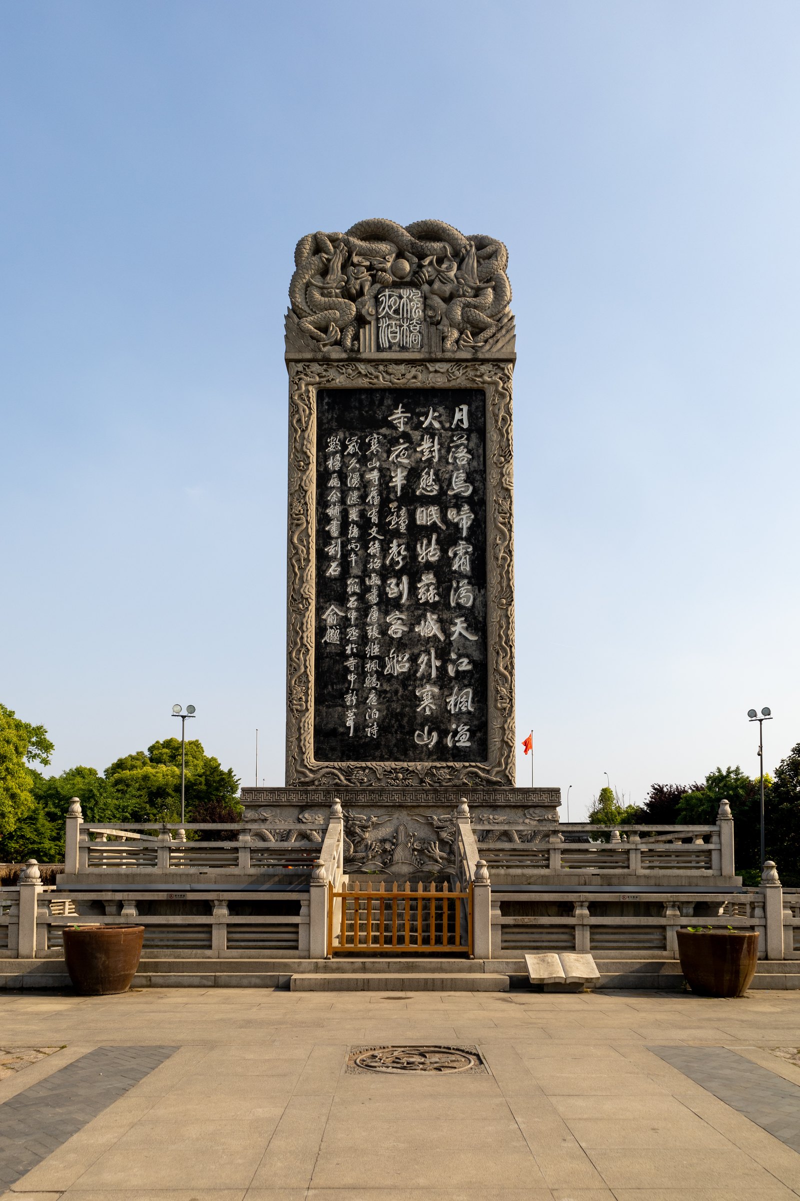 高大的雕花石碑立在石栏围台内,深色碑面刻着多列书法文字。
