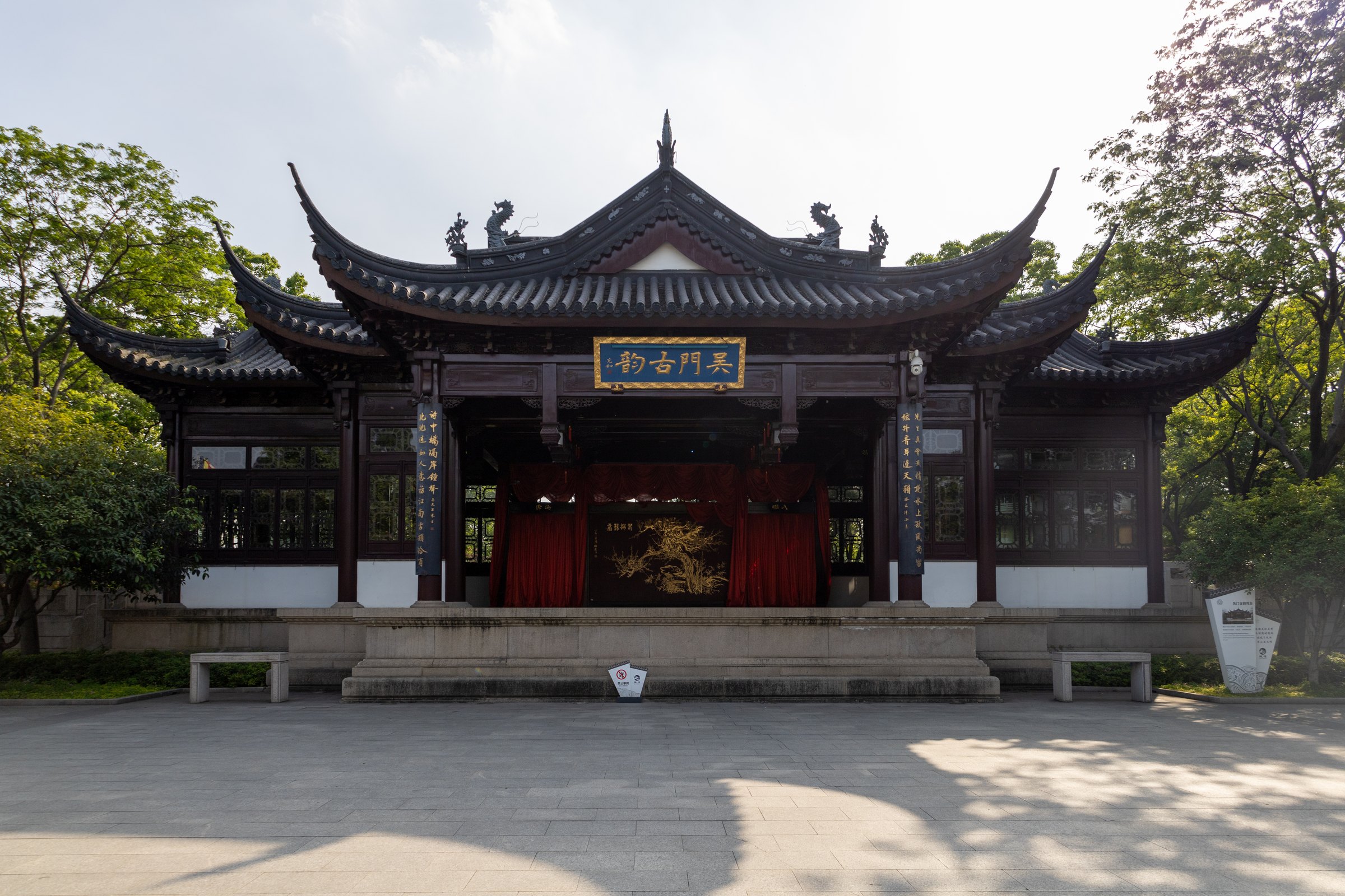 一座灰瓦翘檐戏台面向空旷铺地,台内有红幕和金色图案。
