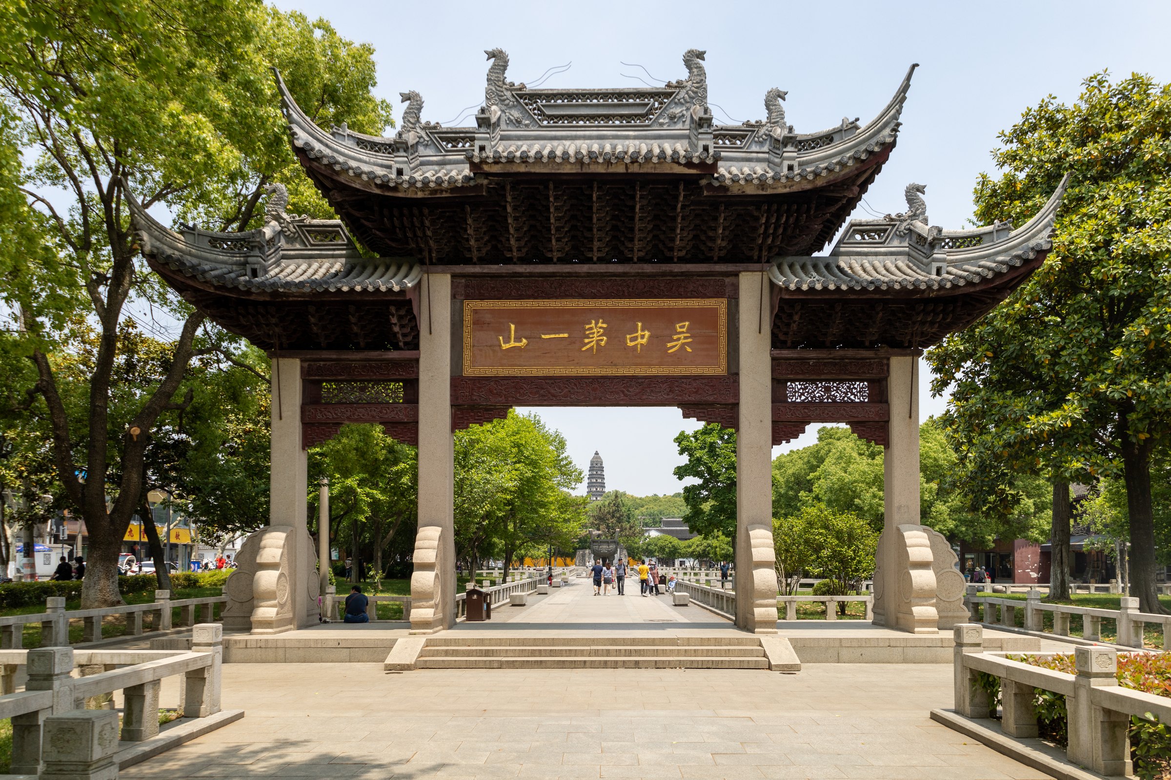 重檐牌楼横跨石铺步道,中央门洞远处可见一座多层塔。