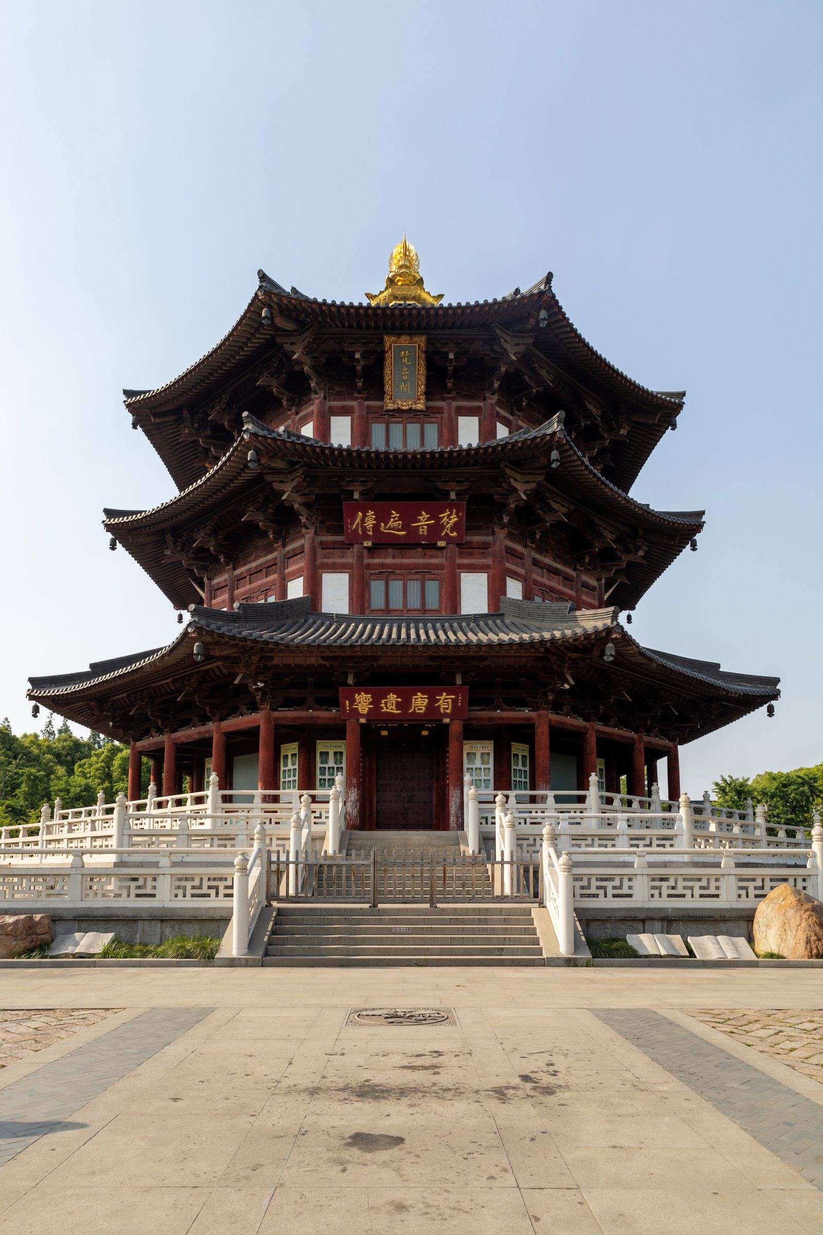 一座红木多檐楼阁位于宽阔石铺地面后方,白栏环绕,顶端有金色装饰。