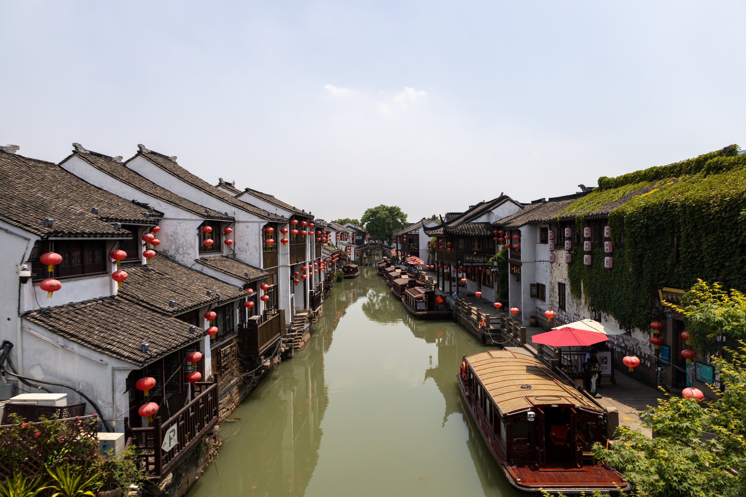 白墙灰瓦建筑分列河道两侧,红灯笼和停泊木船点缀岸边。
